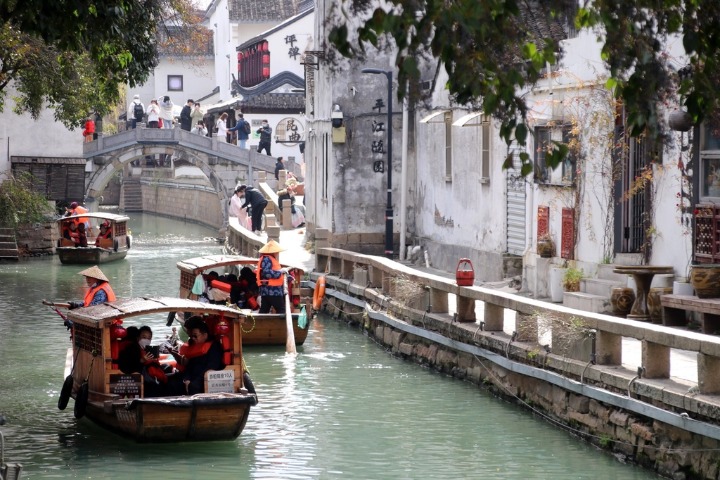 Tourists hop on hand-paddled wooden boats to explore Suzhou water lanes