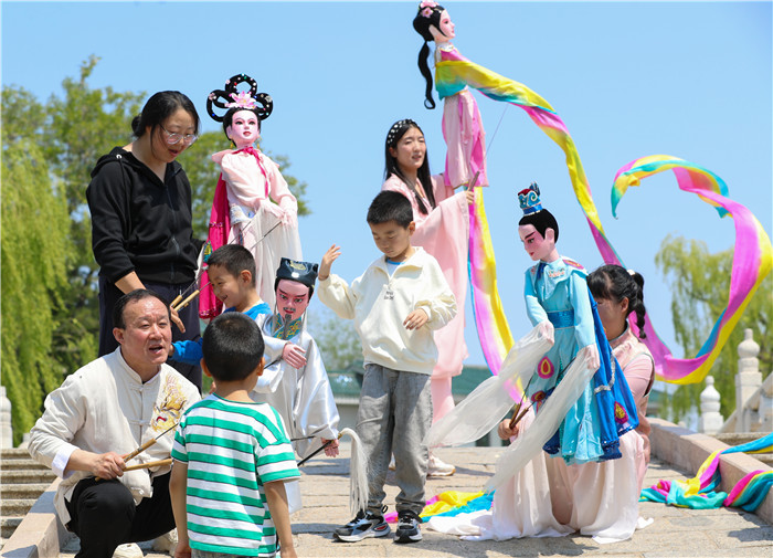 1748241148200049176.jpg 5月11日,姜玉涛和演员们在山东省莱西市月湖公园和小朋友互动。(张进刚 摄)电话13854260100.jpg