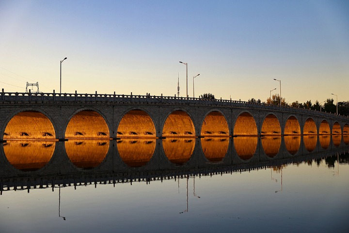 Setting sun shining through bridge draws photographers
