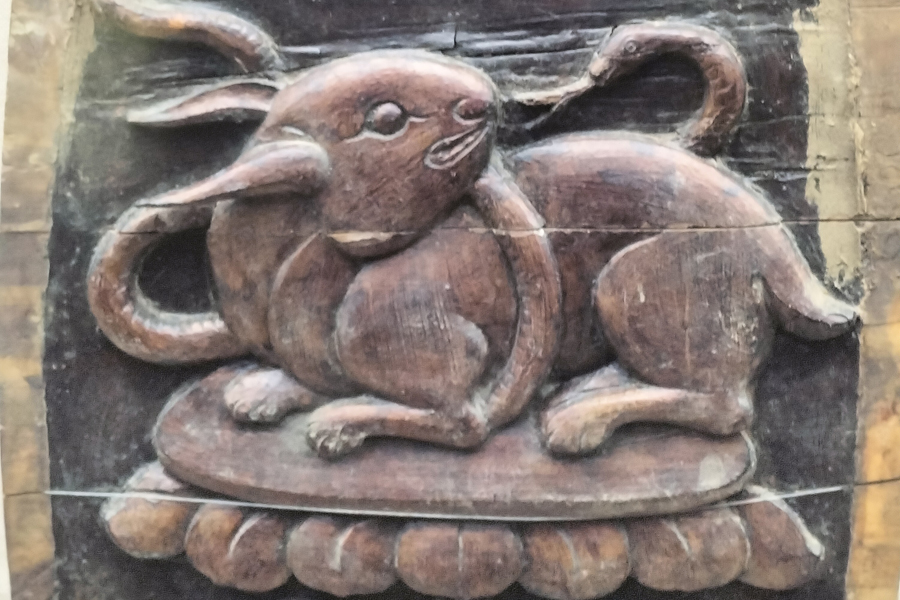 Wooden burial item with rabbit and snake relief