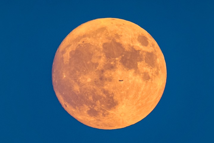 Airplane pierces the super moon’s glow over Pingyao