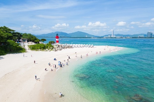 Tourists enjoy the sea view on the white sandy beach in Sanya