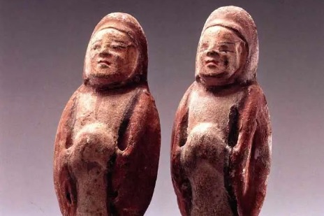 A pair of 6th century painted pottery figurines wearing hoods