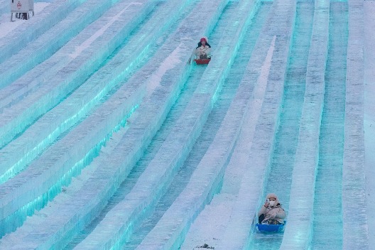 Tourists experience super ice slide at Harbin Ice-Snow World